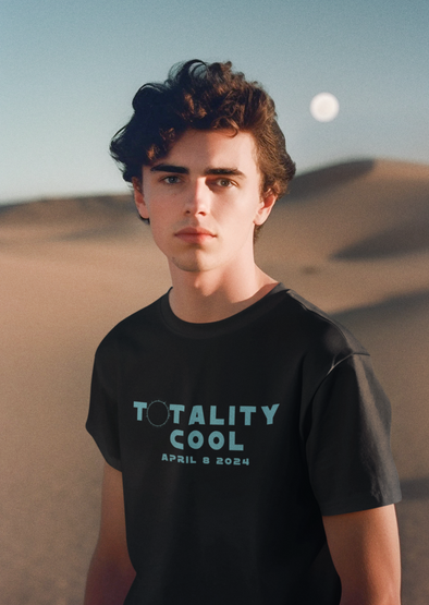 TOTALITY COOL eclipse design on a black t-shirt with a young man wearing tee with dunes and sun in background