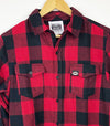 close up red black flannel longsleeve shirt with faux leather black PEC oval label on left pocket prince edward county